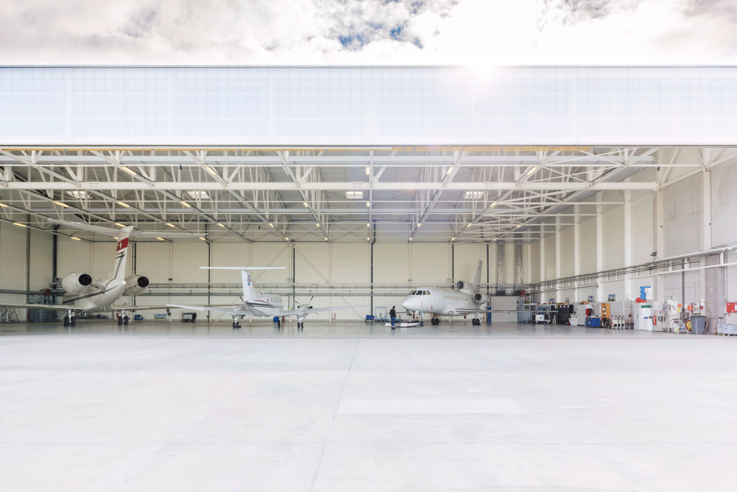 open hangar with three parked aircrafts inside